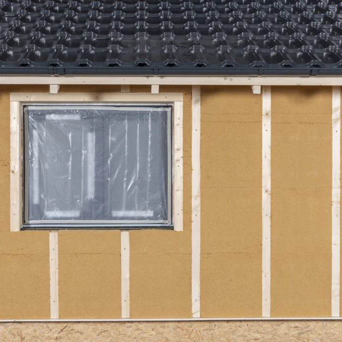 Fenster in neu aufgebauter, gedämmter Fassade mit modernem Material vorbereitet für DIY-Verputzarbeiten.