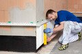 Die Sockeldämmplatte wird mit der Wasserwaage ausgerichtet.