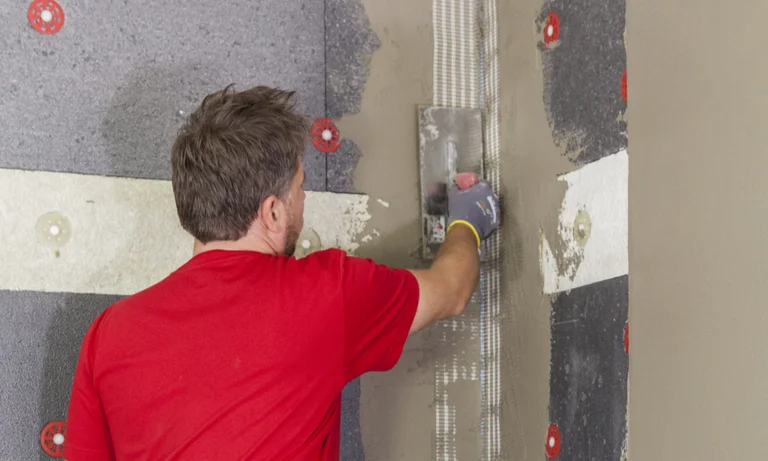 Heimwerker trägt Putz auf Wand mit Dämmmaterial auf.