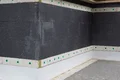 Fassadendämmung mit dunklen Dämmplatten und Befestigungsankern zur Energieeffizienzsteigerung und Wandisolierung.