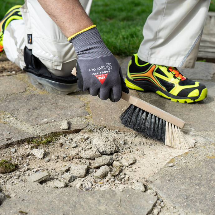 Betonfläche wird mit einem Besen gründlich von Staub und Schmutz befreit.