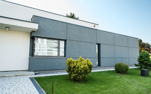Moderne Fassade mit grauen Platten, umgeben von gepflegtem Garten, ideal für kreative Heimwerkerprojekte.
