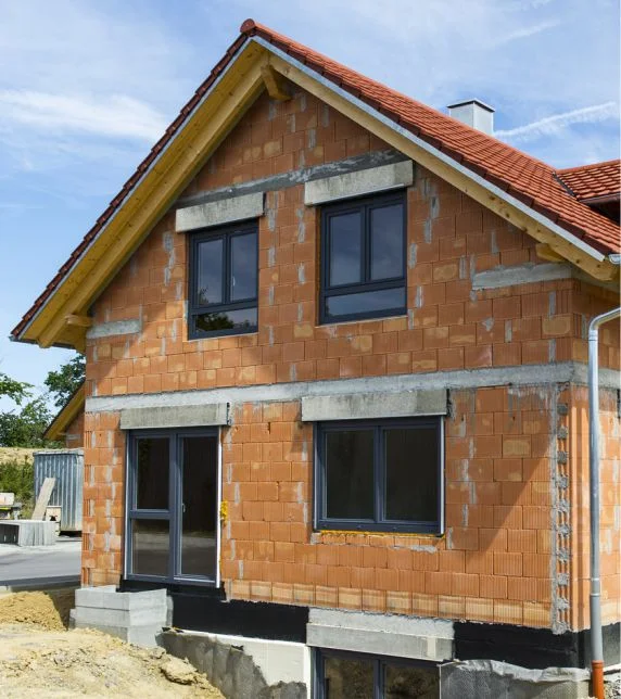 Unverputztes Neubauhaus mit Betonsturz und Ziegelmauerwerk, bereit für Fassadenverputz mit Baumit Produkten.