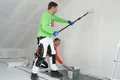 Der Airless- und Rollspachtel Silikat wird von einer Person mit der Walze aufgetragen und die andere Person glättet den Spachtel ab.