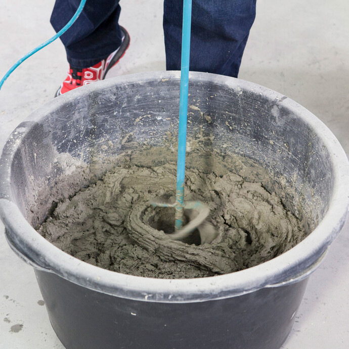 Detailfoto: Klebemörtel wird im Mörtelkübel mit einem elektrischen Rührwerk angemischt.