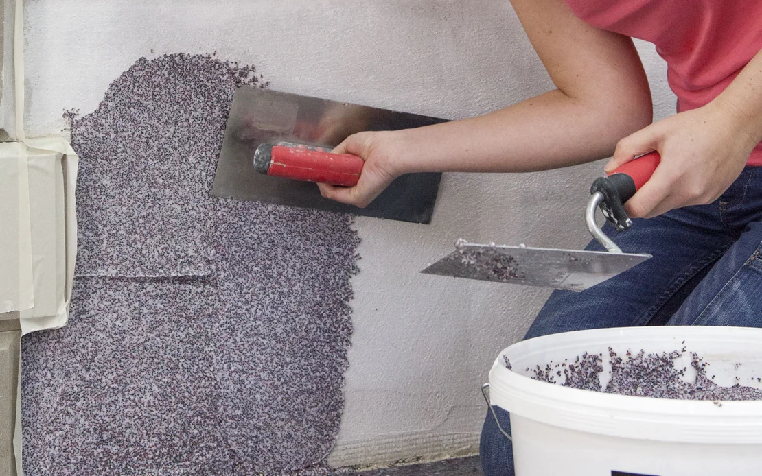 Der Baumit Mosaikputz,, Buntsteinputz, wird mit einer rostfreien Gl&auml;ttkelle aufgzogen.