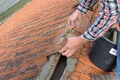 Der Baumit Dachdeckermörtel grau wird aufgetragen und die Dachplatte eigebettet.