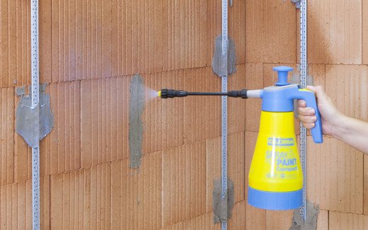 Grundierung wird auf das stark saugende Mauerwerk aufgesprüht, damit danach die Wand verputzt werden kann.