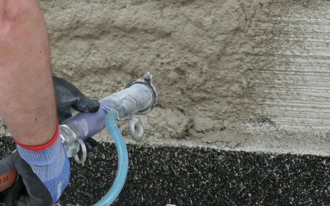 Der Sockel wird mit einer Putzmaschine verputzt.