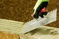 Arbeiten mit Zahnkelle: Mörtelschicht auf Ziegelstein gleichmäßig auftragen, ideal für DIY-Mauerprojekte.