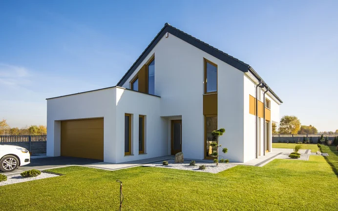 Modernes Einfamilienhaus mit weißer Fassade und gepflegtem Garten, ideal für Heimwerkerprojekte im Außenbereich.