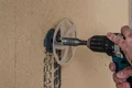 Bohrmaschine befestigt Dübel in Dämmplatte zur Wandisolierung.