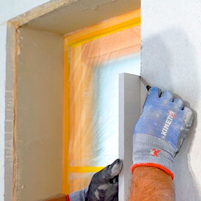 Person markiert sich die Größe der Laibungsplatte, in dem sie die Platte in die Laibung setzt und den Überstand mit einem Bleistift markiert. So kann die Platte exakt zugeschnitten werden.