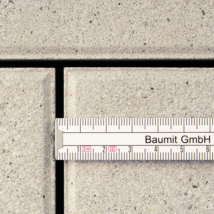 Bevor die Betonsteinplatten mit dem Pflasterfugenmörtel Fix verfugt werden, wird die Mindestfugenbreite mit einem Lineal überprüft.