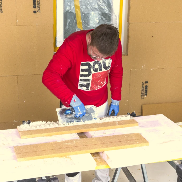 Heimwerker trägt mit Rakel eine Putzschicht auf Wand auf, unterstützt von Baumit-Produkten, DIY-Projekt in der Renovierung.