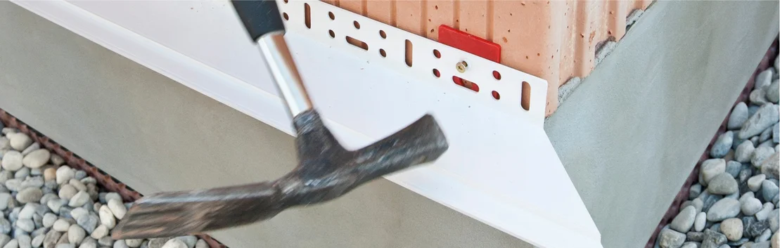Eckprofil f&uuml;r Fassadend&auml;mmung: Montage mit Hammer an einer Hauswand, vorbereitet f&uuml;r weitere D&auml;mmarbeiten.