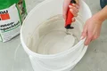 Innenspachtelmasse im Eimer mit Spachtel anrühren; Vorbereitung für Renovierungsarbeiten. Ideal für glatte Wände und Decken.