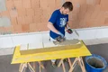 Heimwerker verlegt Dämmstoffplatten auf einem Holztisch, um eine Wand zu dämmen.