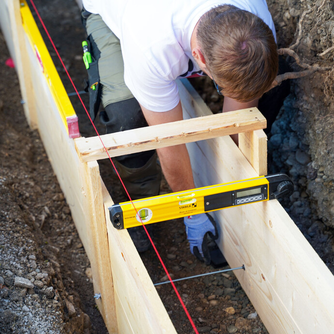 Sobald alle Schalungselemente eingesetzt und miteinander verschraubt sind, wird die Schalung waagerecht ausgerichtet. Dafür wird eine lange und kurze Wasserwaage benötigt.